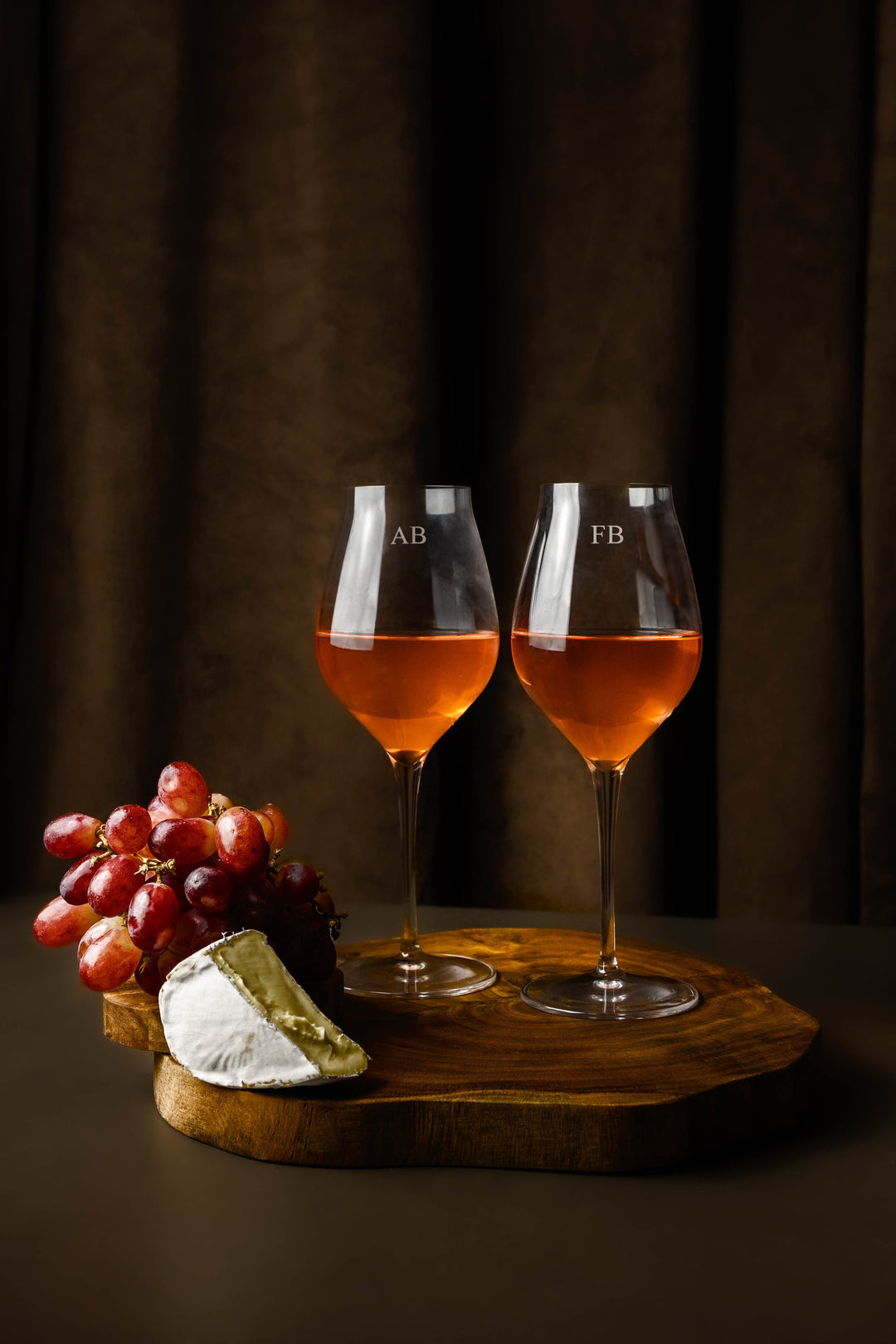 Set of two Abigail white wine glasses on a wooden board. Wine glasses are engraved with a monogram.